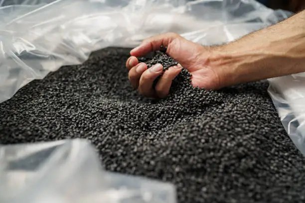 close up of male hand holding plastic polymer granules